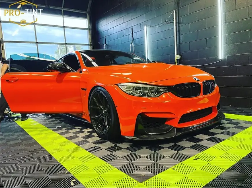 Orange BMW M3 on the green checker floor of the Pro-Tint bay